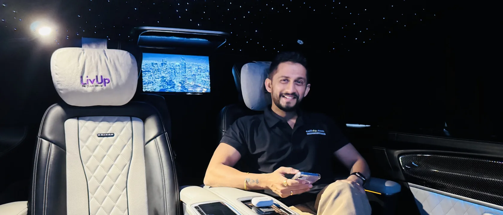 Digital Pratik smiling in the back seat of a car, his phone in his hand