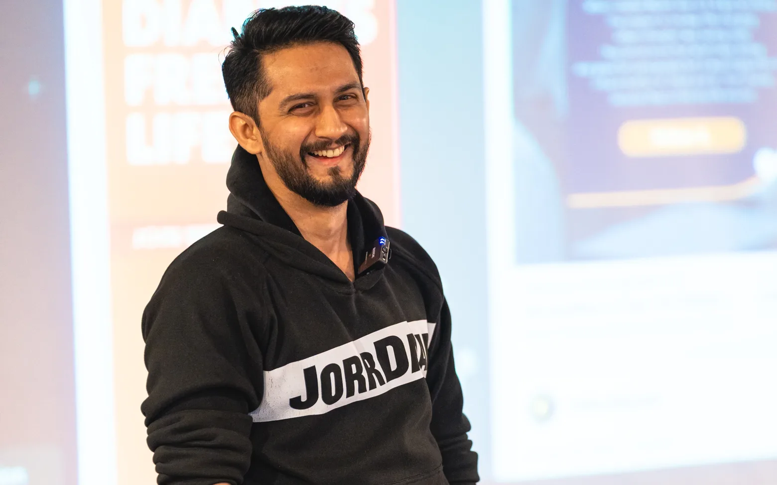 Digital Pratik laughing on stage in a black JorrDaar hoodie