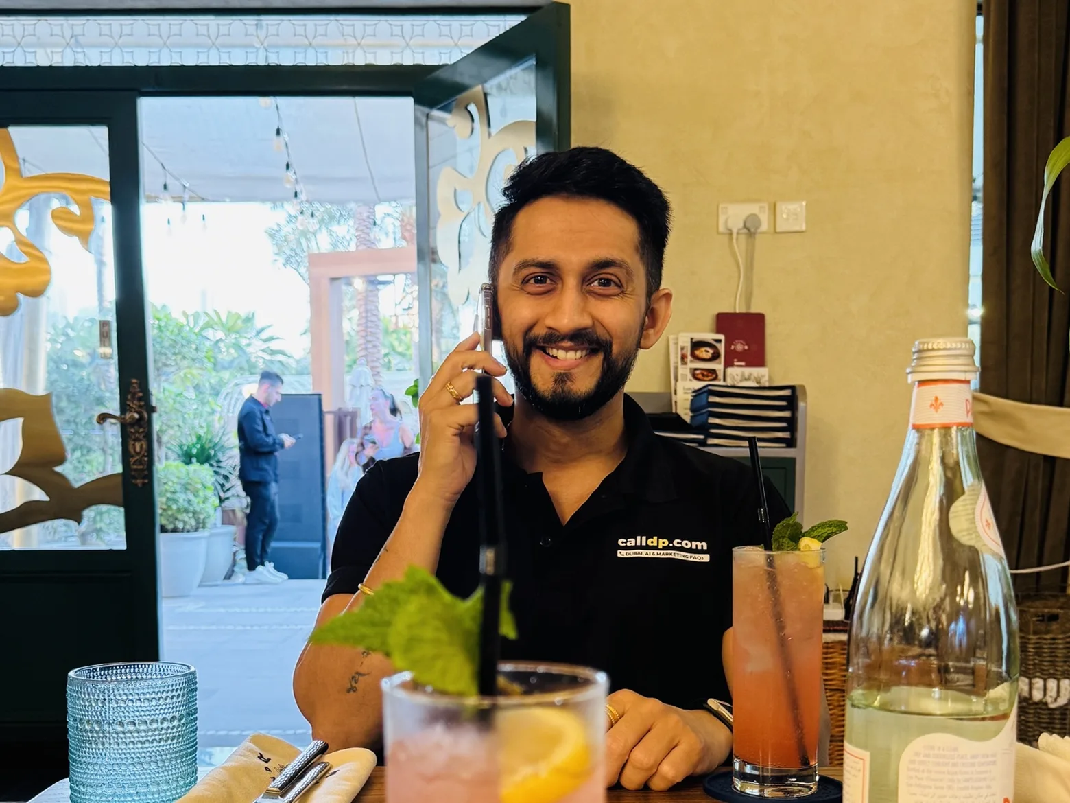 Digital Pratik smiling on a phone call at a restaurant table