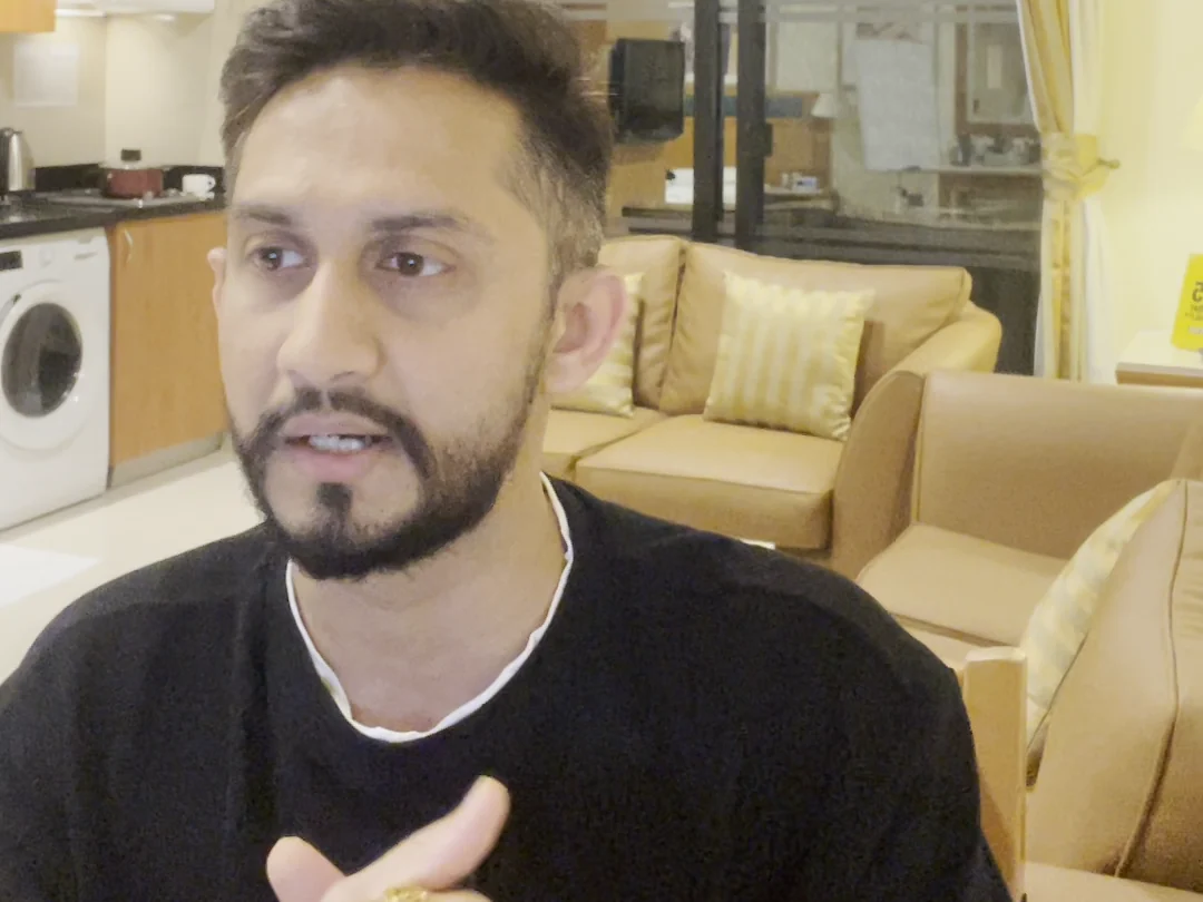 Digital Pratik talking with his hands at the 10 October 2026 recording, filmed on his phone in his living room