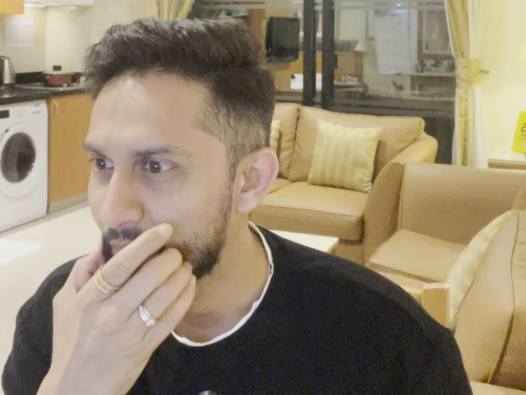 Digital Pratik listening with his hand on his chin at the 10 October 2026 recording, filmed on his phone in his living room