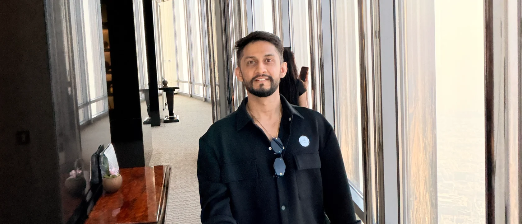 Digital Pratik, digital pratik stands in a hotel lobby holding a selfie stick, smiling slightly at the camera