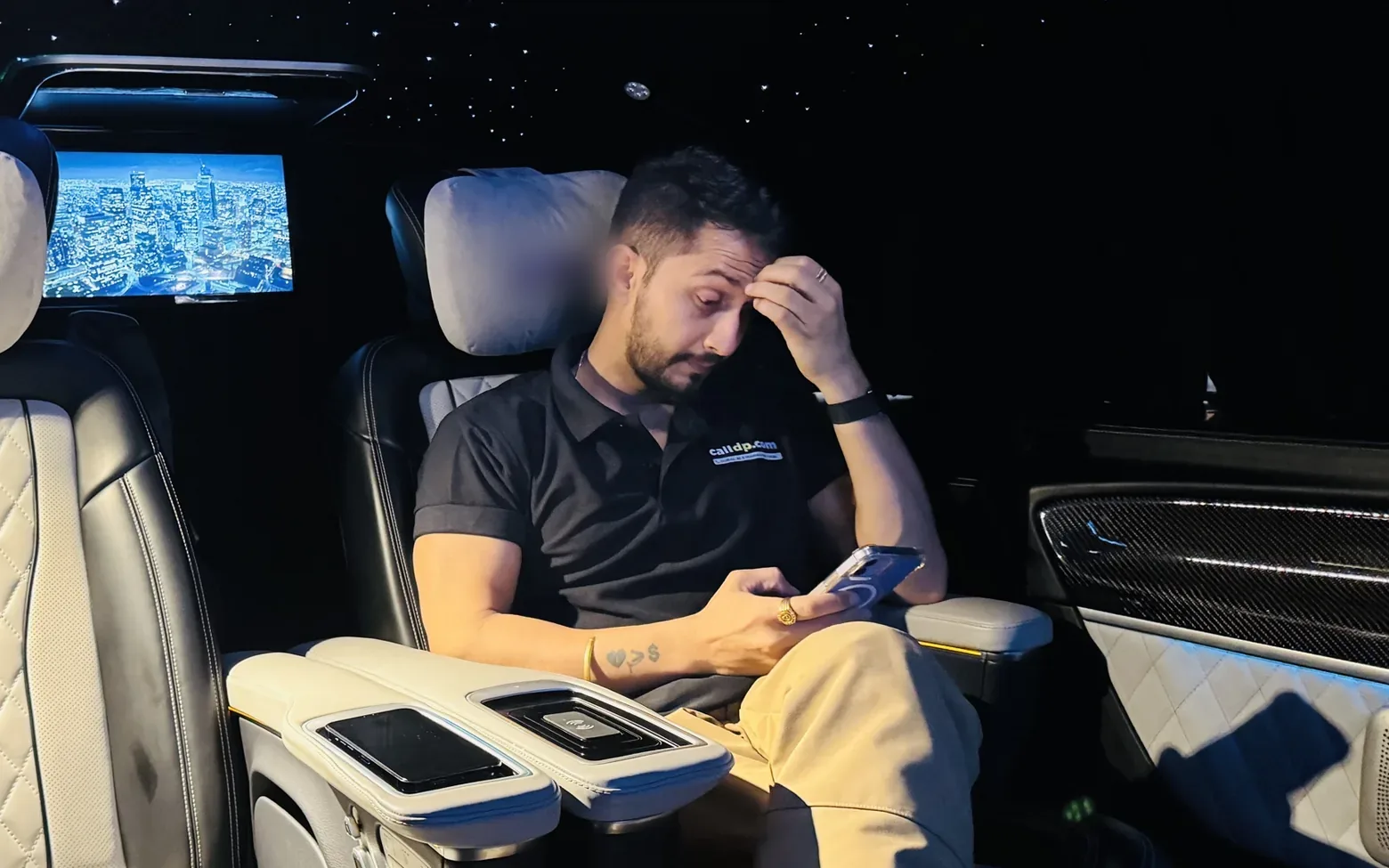 Digital Pratik in the back of a car at night, looking down at his phone with a hand on his forehead