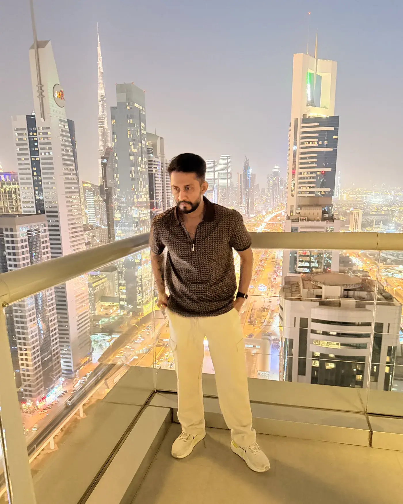 Digital Pratik on a high balcony in Dubai, the city lit up behind him