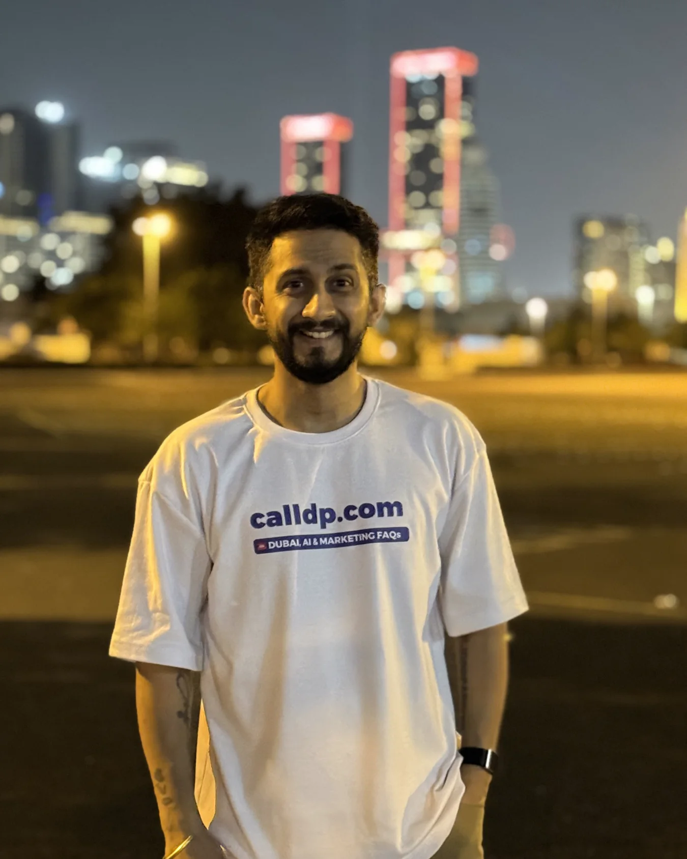 Digital Pratik smiling at the camera at night, the Dubai skyline behind him