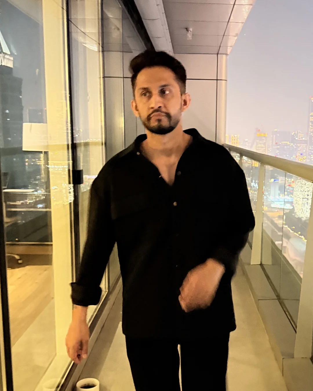 Digital Pratik walking along a high balcony in Dubai at dusk