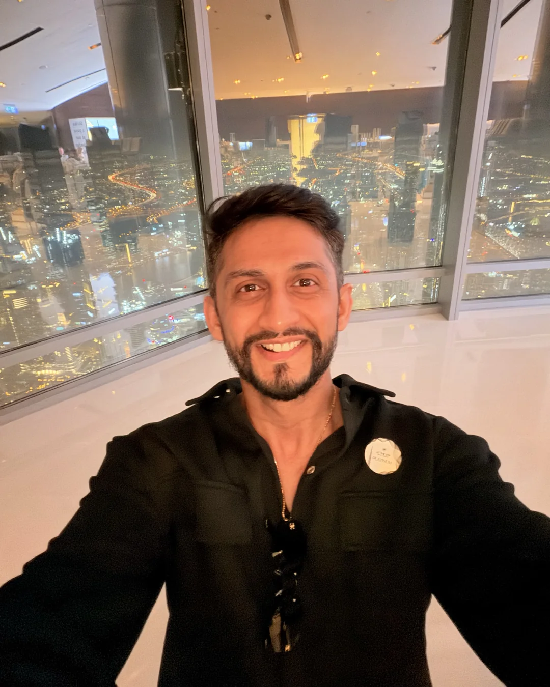 Digital Pratik smiling, the lights of Dubai at night far below him
