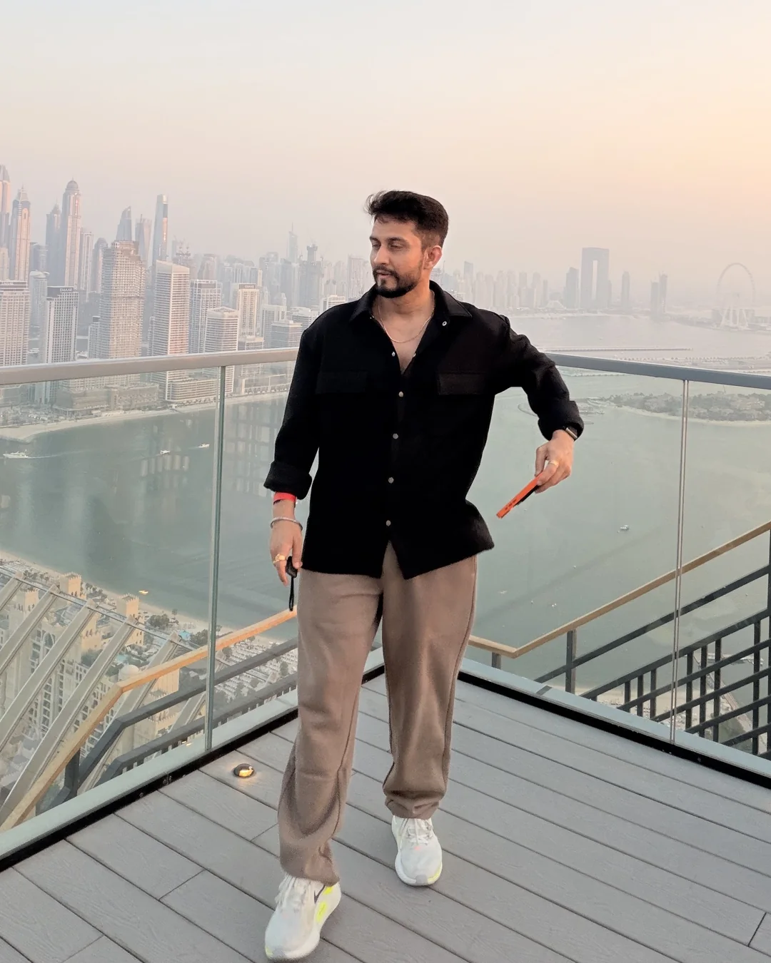 Digital Pratik on a high deck over the sea, the Dubai skyline behind him