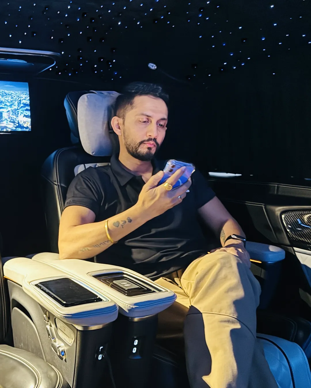Digital Pratik looking at his phone, seated in a car at night