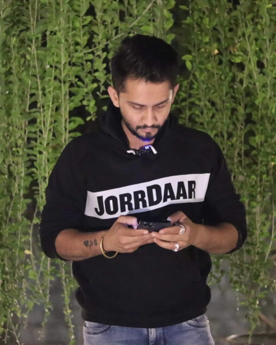Digital Pratik in a JorrDaar hoodie, looking at his phone