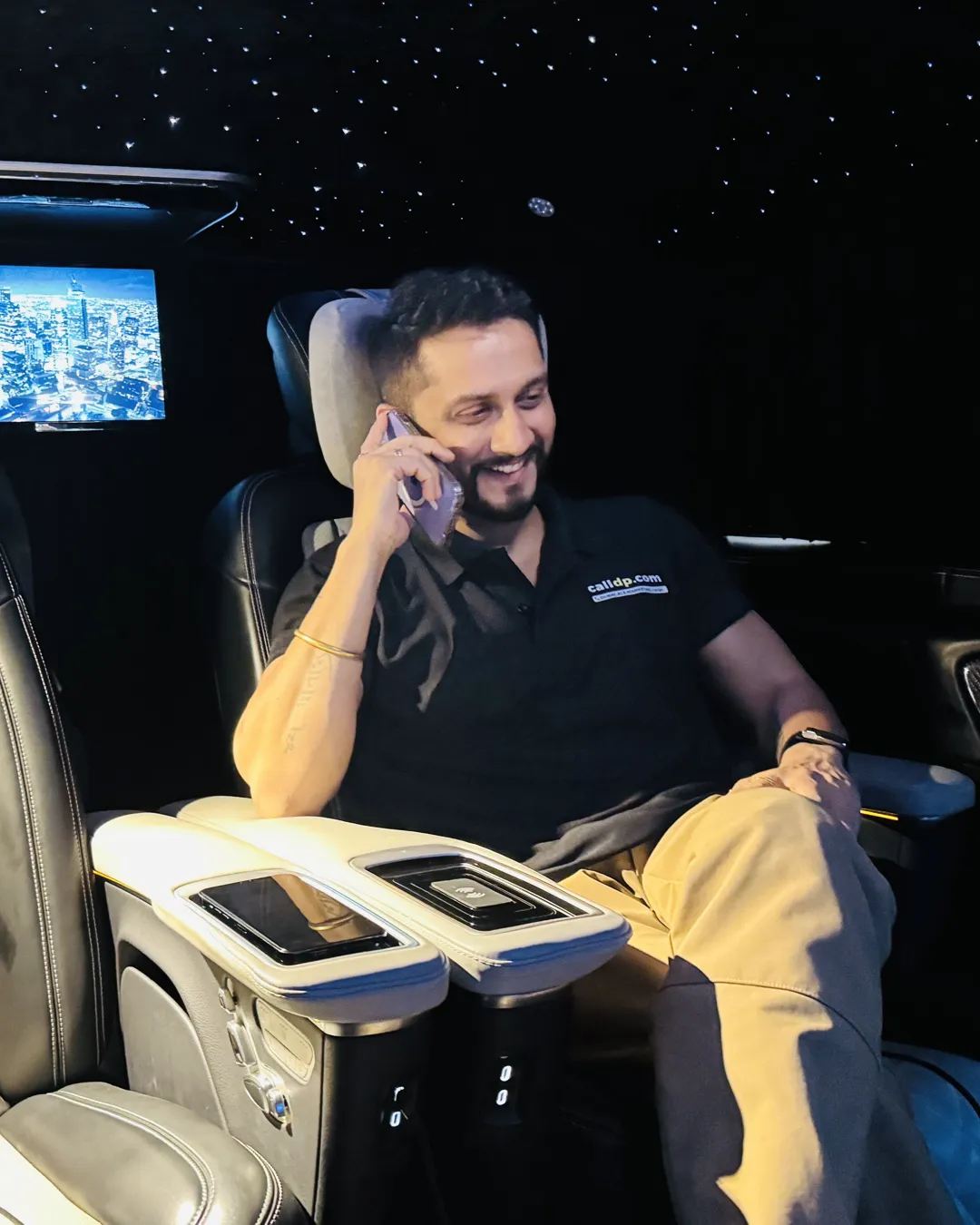 Digital Pratik laughing on a phone call, seated in a car at night