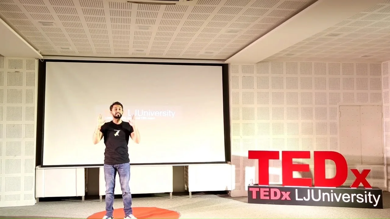 Digital Pratik speaking on the TEDx stage at TEDxLJUniversity